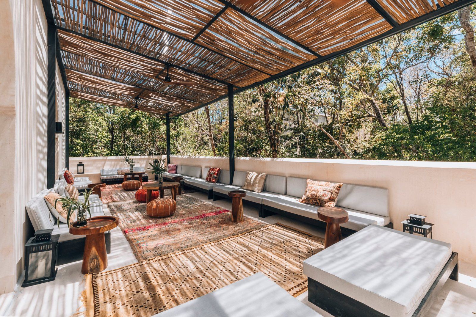 Moroccan terrace with benches, rugs and a wooden pergola